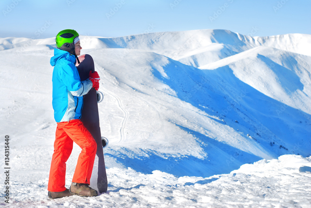 girl standing on a mountain top with snowboard in the hands