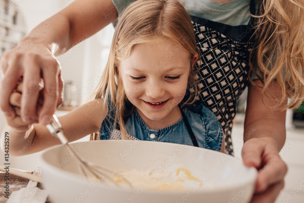 Mother and daughter preparing batter for baking