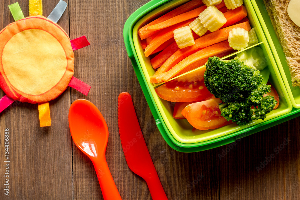 green lunch box for kid on wooden background top view