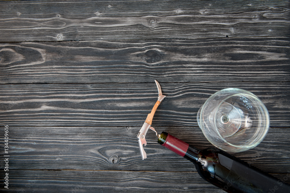 glass wine bottle and corkscrew on wooden background top view