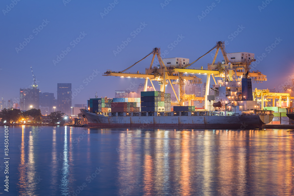 container cargo freight ship with working crane bridge in shipya