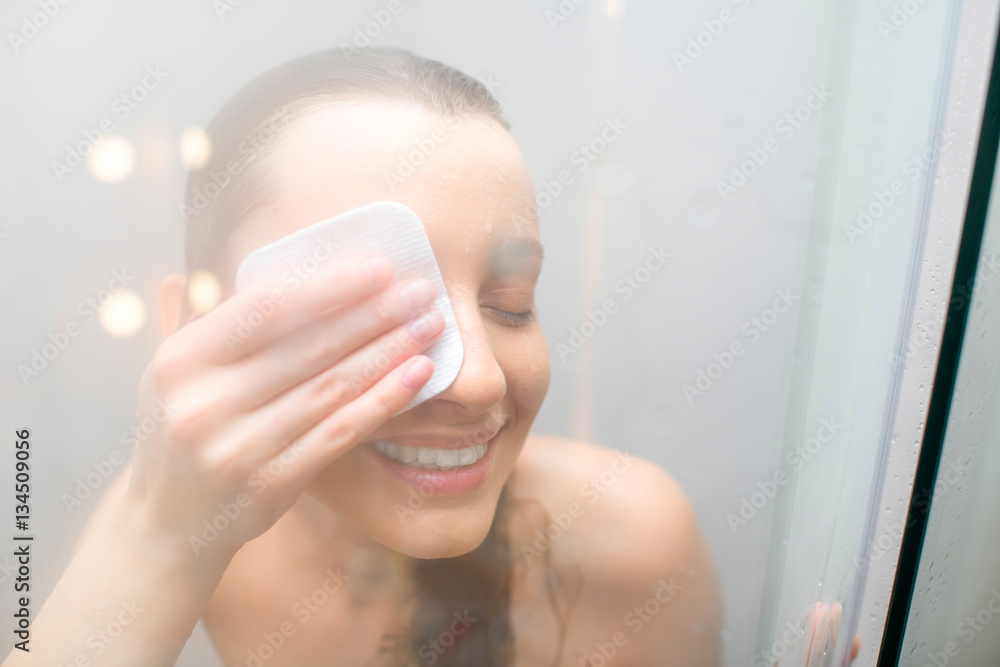 Woman applying cosmetics with cotton swab after the shower