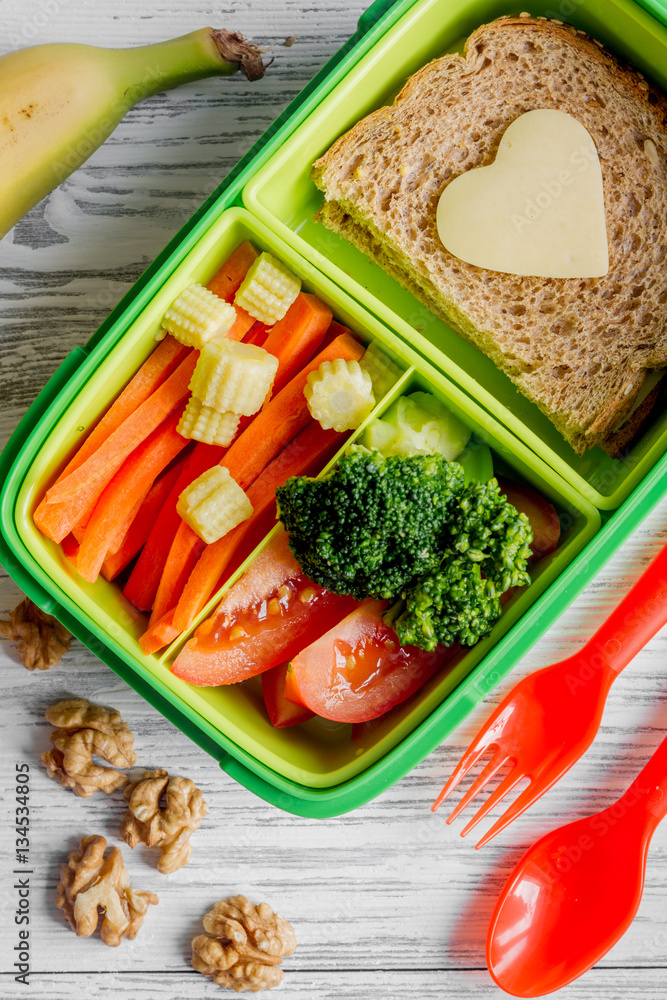 green lunch box for kid on wooden background top view