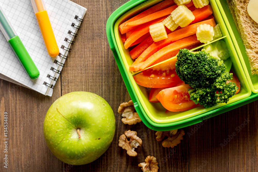 green lunch box for kid on wooden background top view