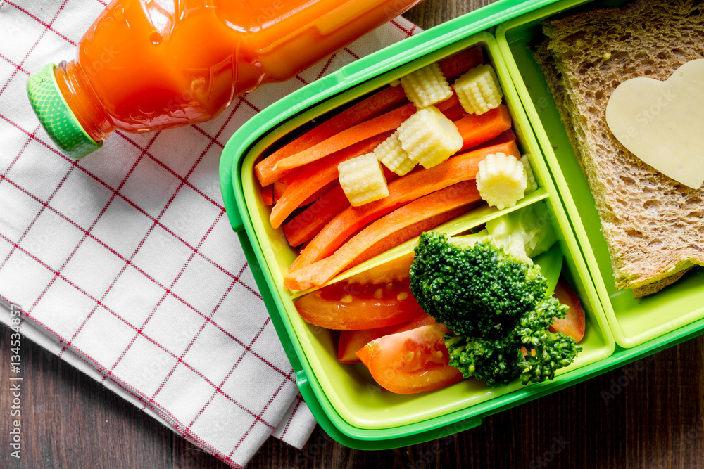 green lunch box for kid on wooden background top view