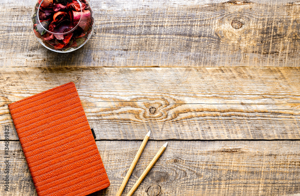 composition of orange notebook with flower sachets on wooden tab