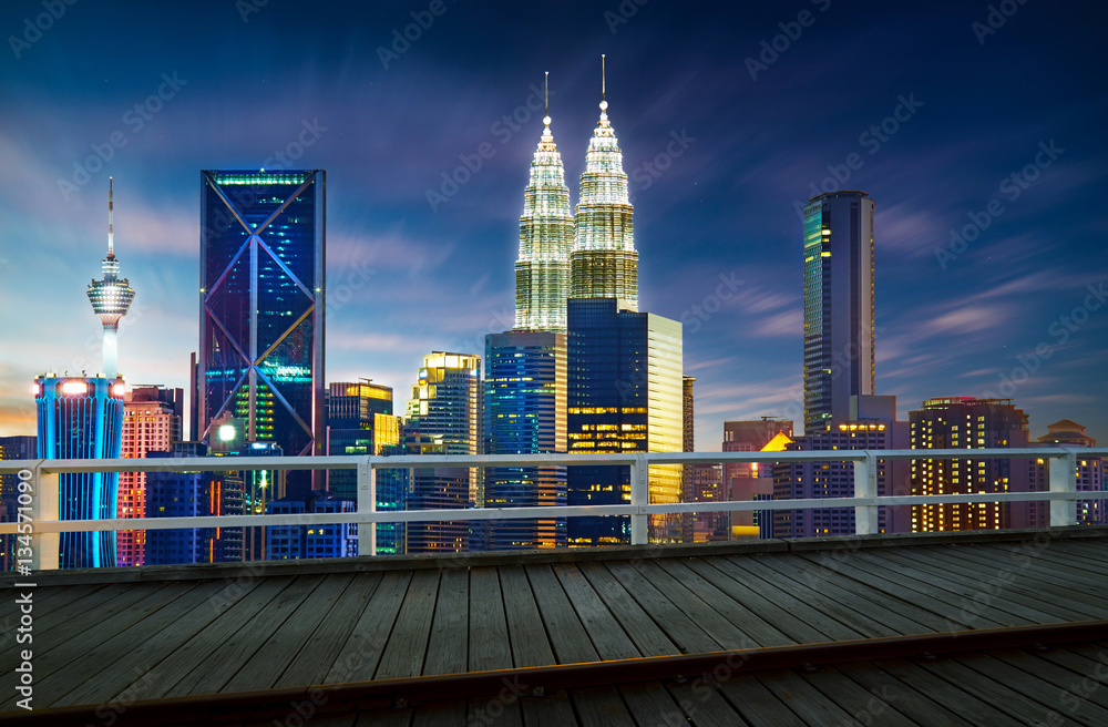 Empty wood floor in front of Kuala Lumpur City skyline with urban skyscrapers at sunset..