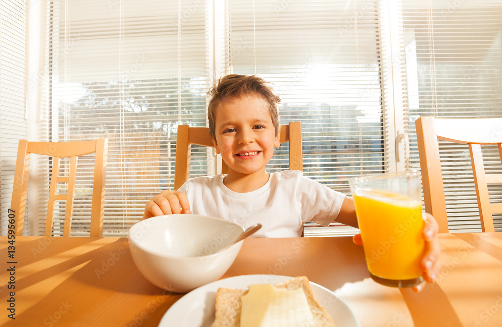 Happy boy holding glass with orange juice