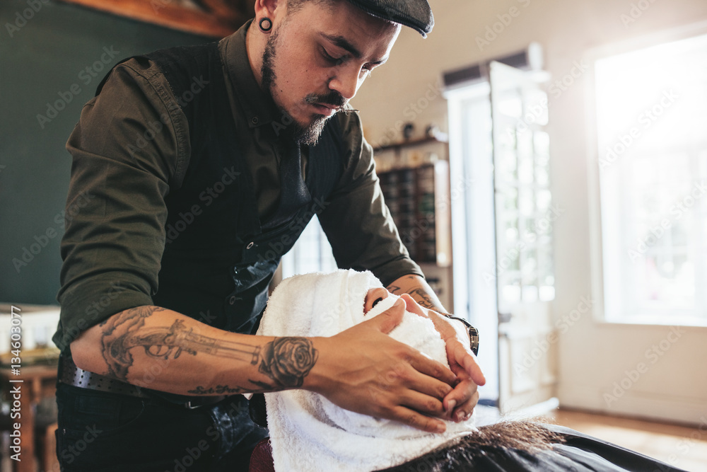 Barber applies a warm cloth on face