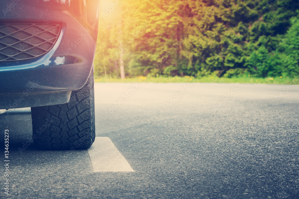 Car on asphalt road on summer day at park. Transportation panoramic background with sunlight