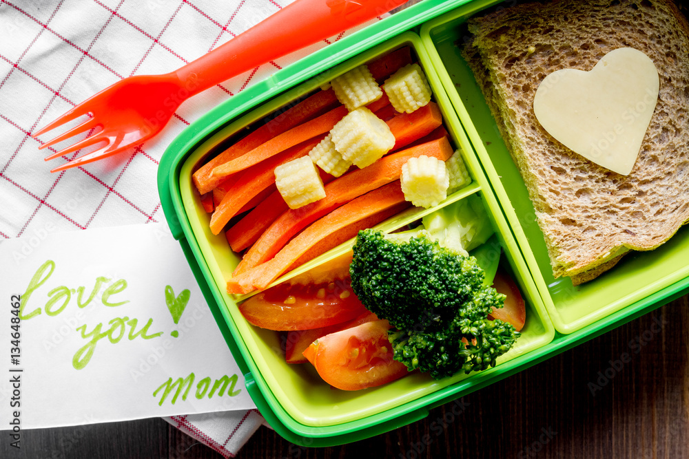 green lunch box for kid on wooden background top view