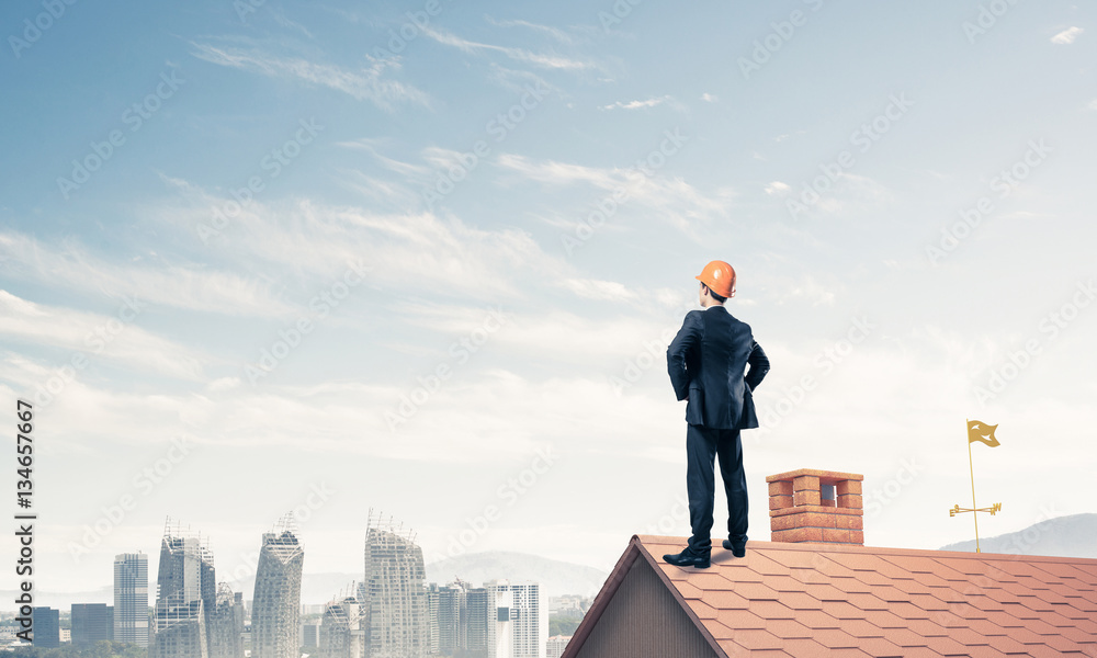 Engineer man standing on roof and looking away. Mixed media