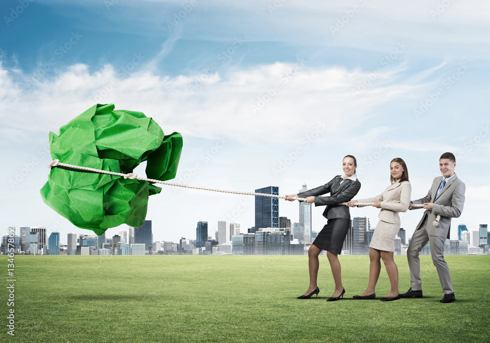 Young business people outdoors and huge paper ball as symbol of creativity