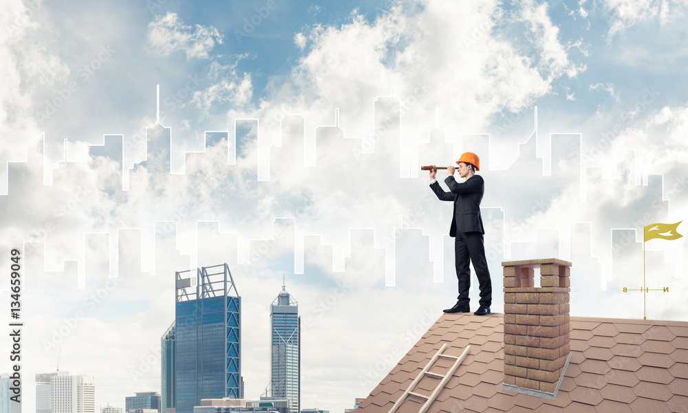 Engineer man standing on roof and looking in spyglass. Mixed med