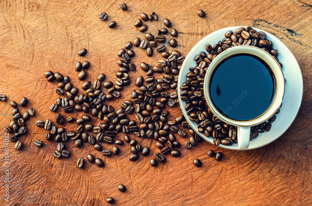 Coffee cup and coffee beans on wood background