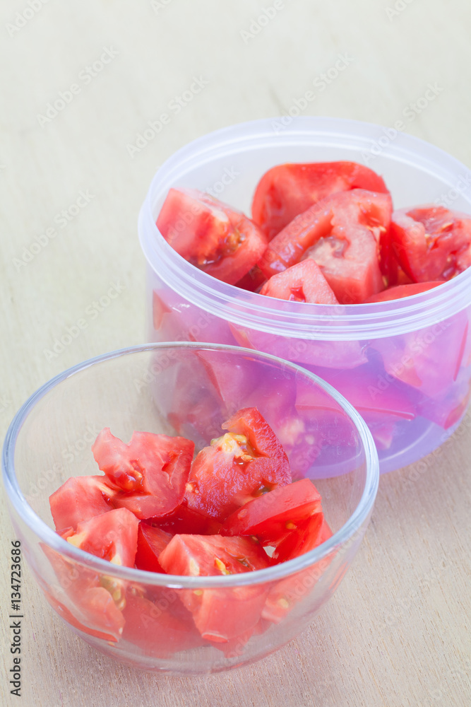 Fresh red tomato slice in glass bowl on wood table background