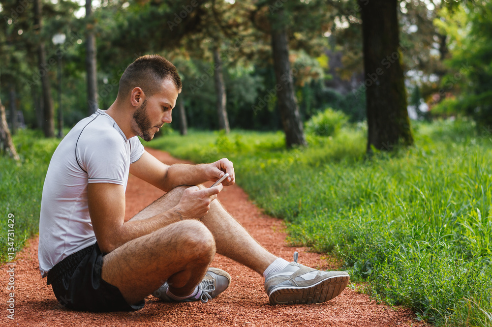 Handsome jogger browsing Internet using his smart phone