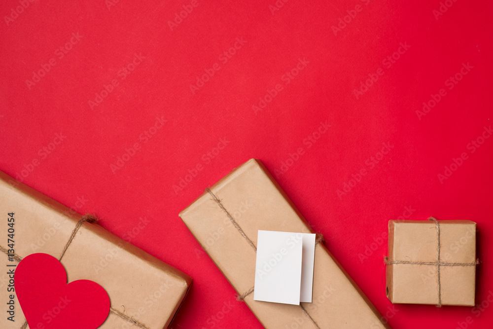 Handmade small gift box with heart symbol on red background.