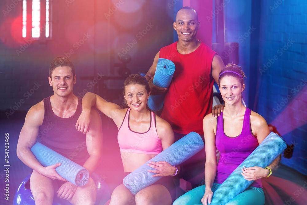 Portrait of smiling friends holding exercise mats 