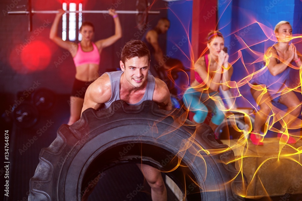 Smiling man lifting tire in gym