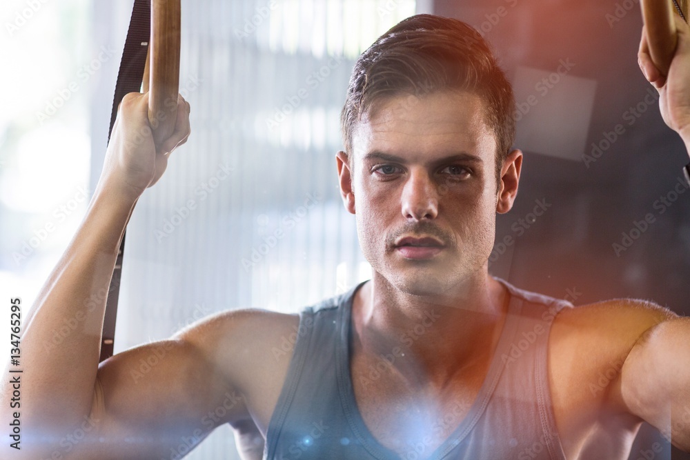 Portrait of young man using gymnastic rings in gym