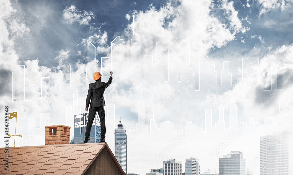 Man architect draw silhouette of modern city on blue sky. Mixed 