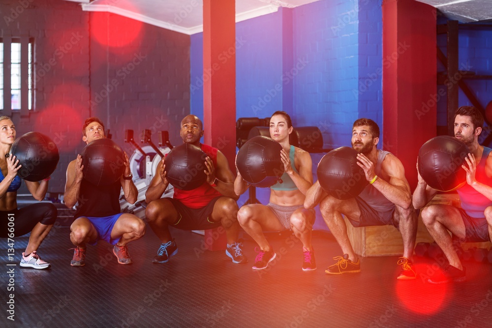 Friends holding exercise ball in gym