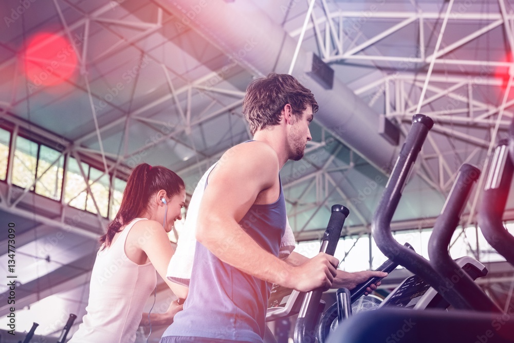 Beautiful woman and man exercising on elliptical machine