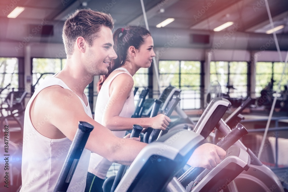 Beautiful woman and man exercising on elliptical machine