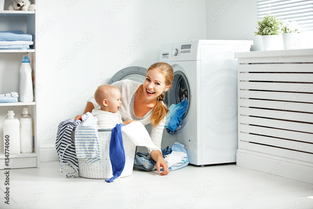 mother housewife with baby engaged in laundry fold clothes into