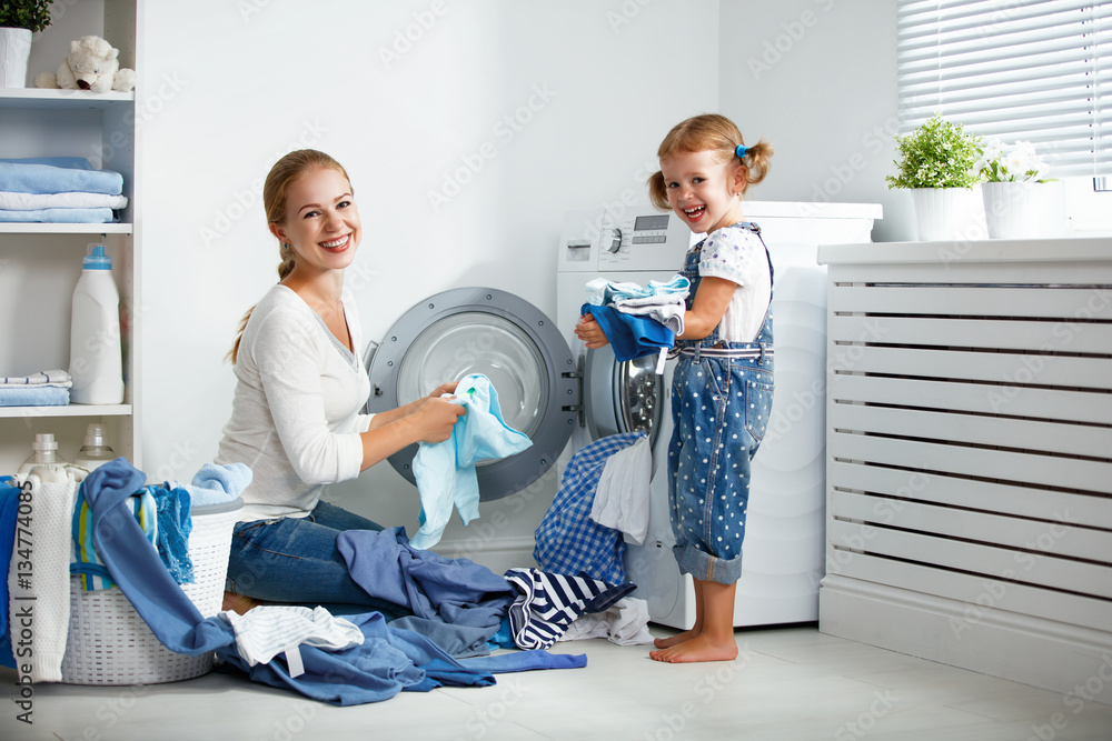 family mother and child girl  in laundry room near washing machi