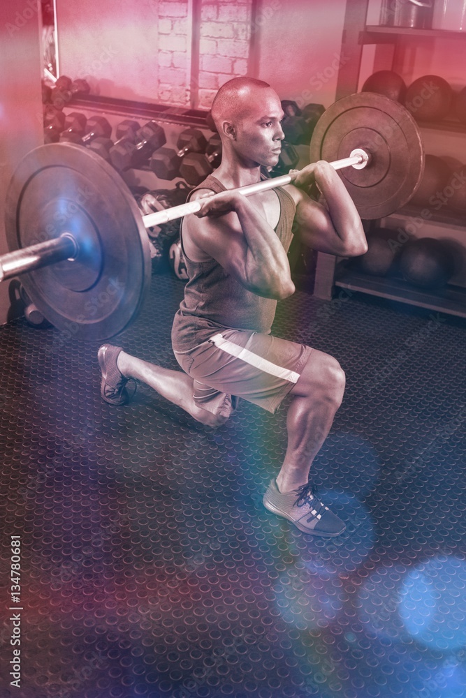 Determined man lifting barbell in fitness studio