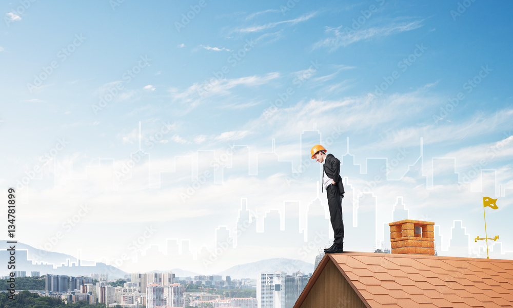 Engineer man standing on roof and looking down. Mixed media