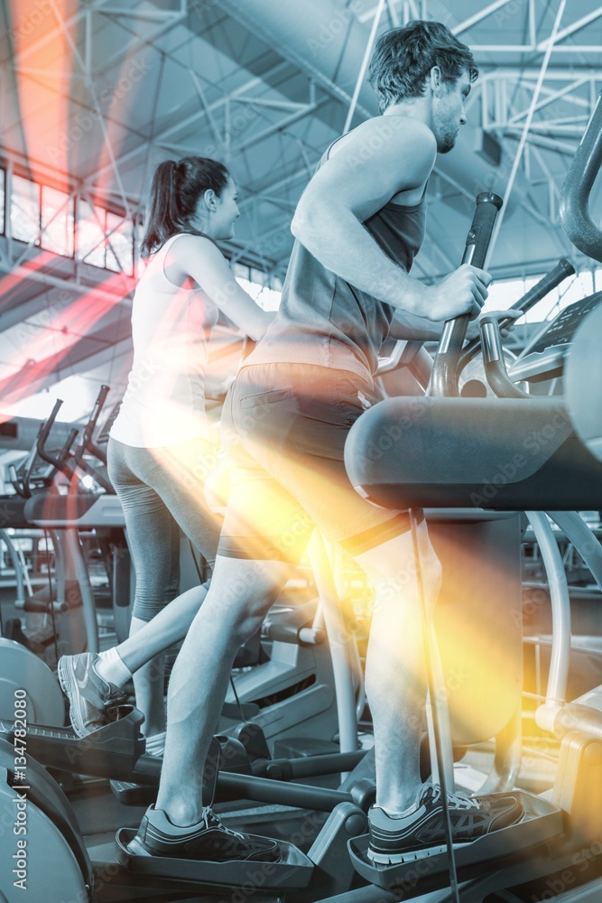 Beautiful woman and man exercising on elliptical machine