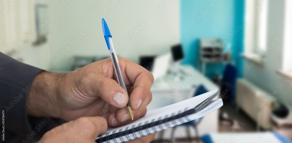 Composite image of close up of man writing in spiral book