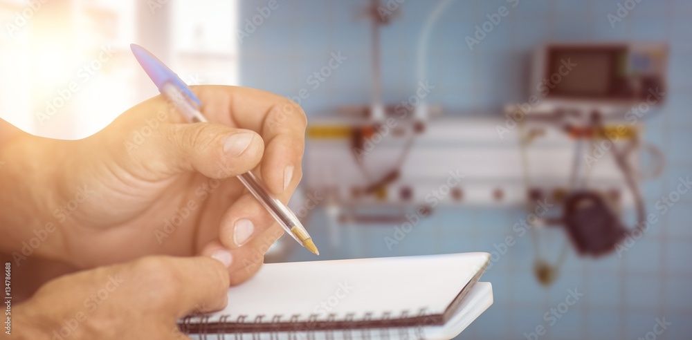 Composite image of close up of man writing in notepad