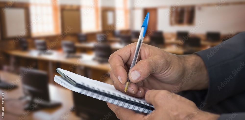 Composite image of close up of man writing in spiral book