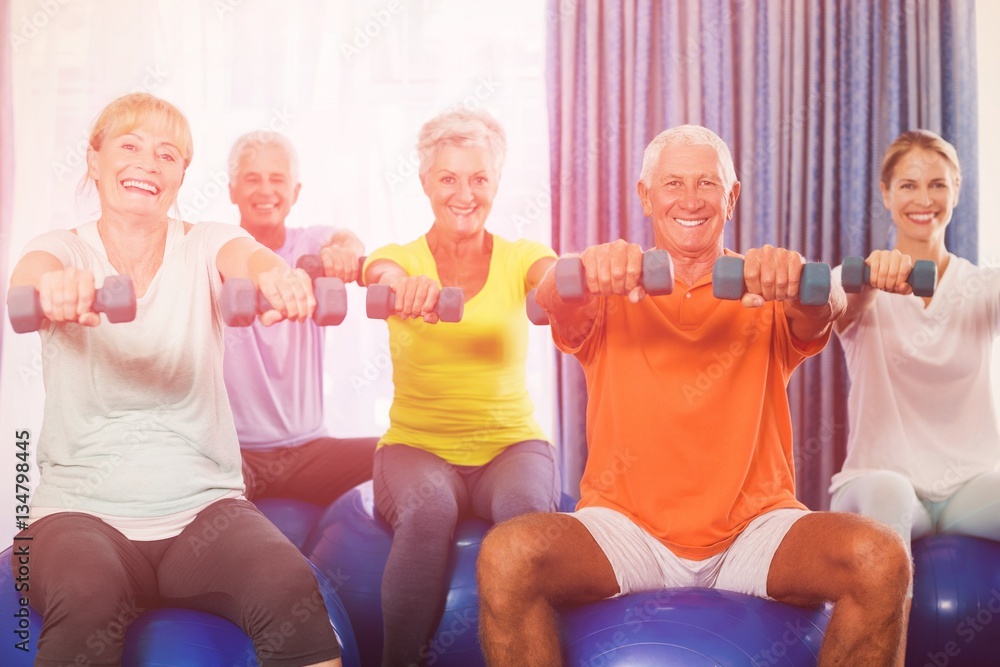 Portrait of seniors using exercise ball and weights