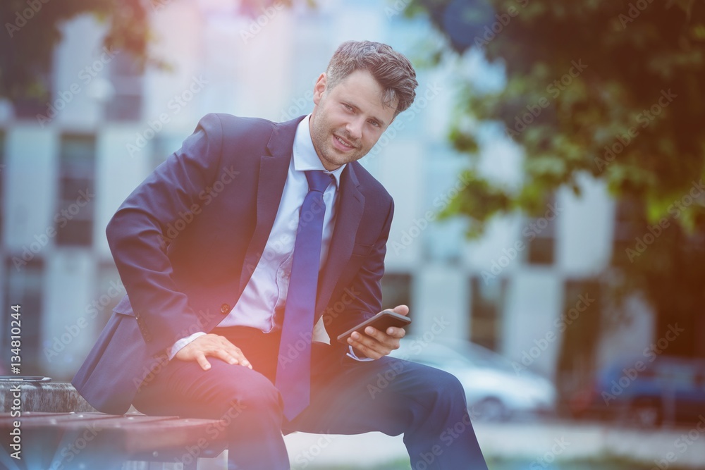 Portrait of handsome businessman holding mobile phone