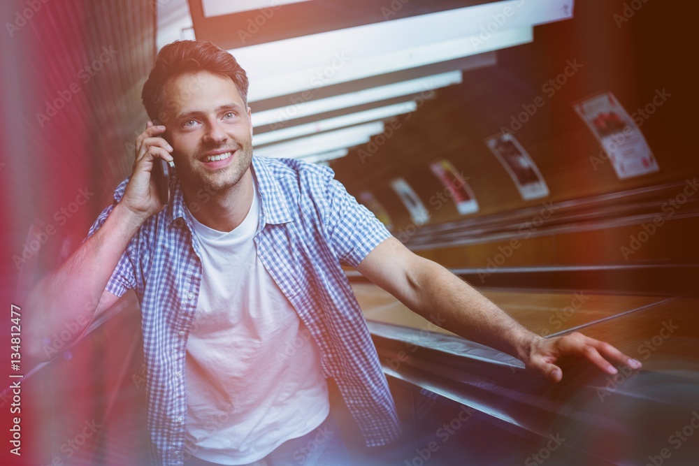 Handsome man using mobile phone on escalator