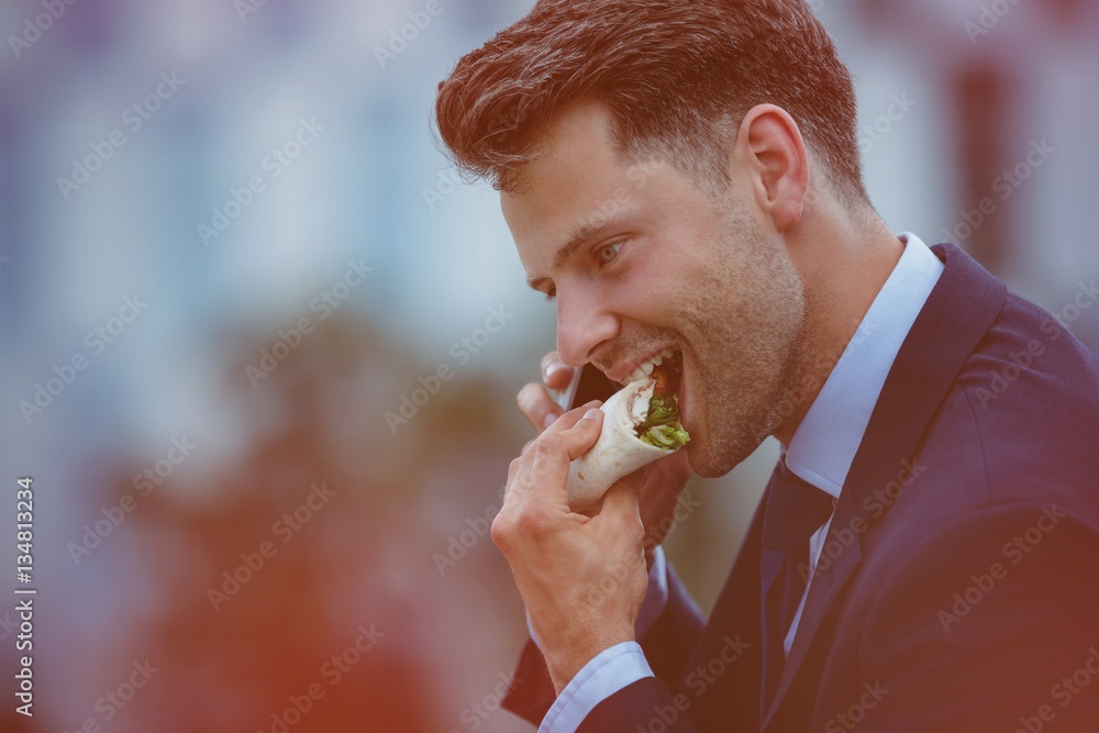 Handsome businessman eating snacks