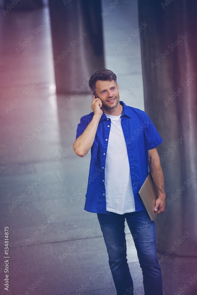 Handsome man holding laptop and talking on mobile phone