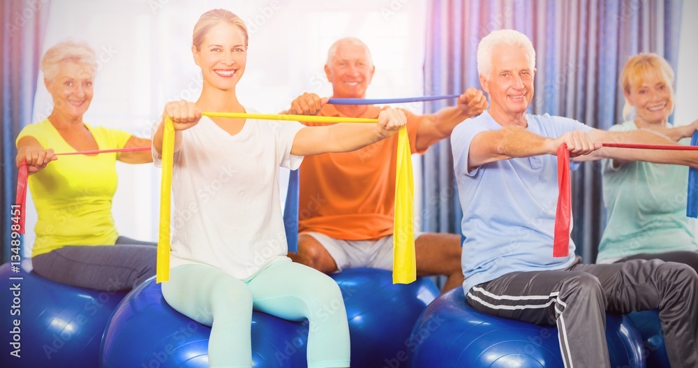 Portrait of seniors using exercise ball and stretching bands