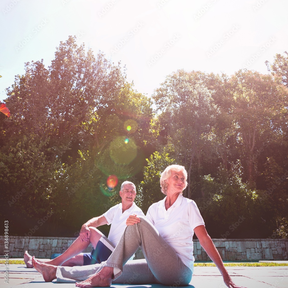 Senior couple exercising at poolside against sky