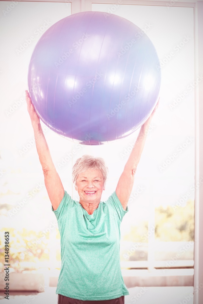 Portrait of happy woman holding blue exercise ball