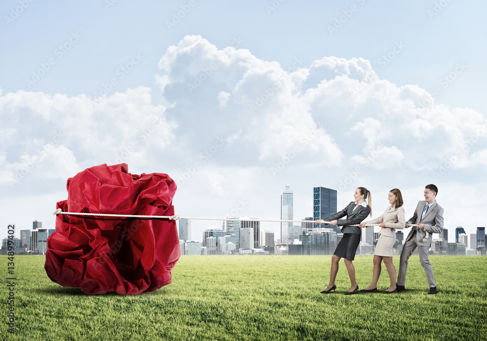 Young business people outdoors and huge paper ball as symbol of creativity