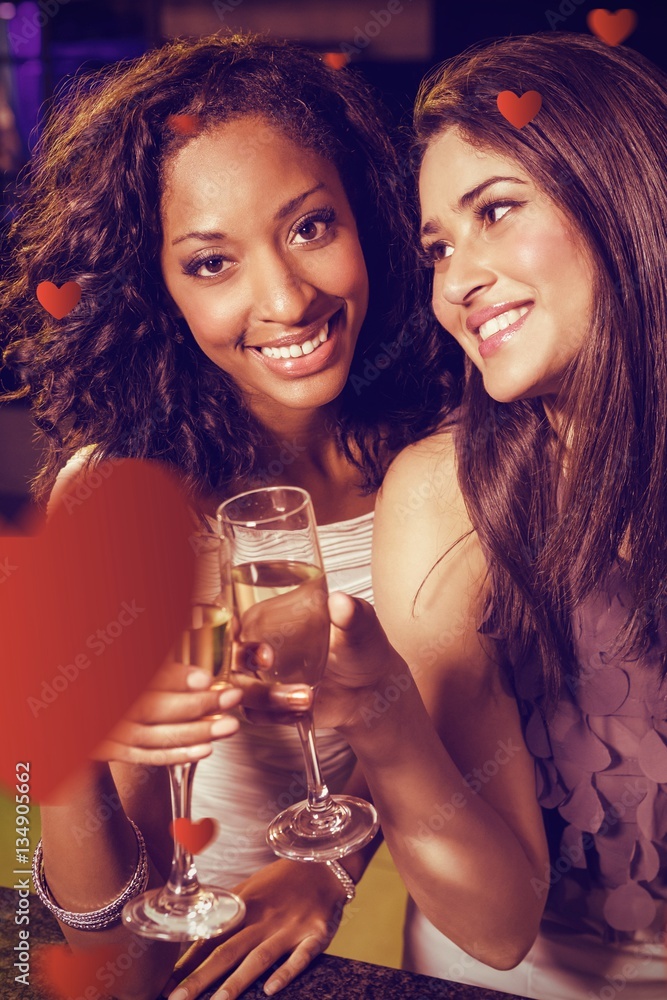 Composite image of happy young women having champagne