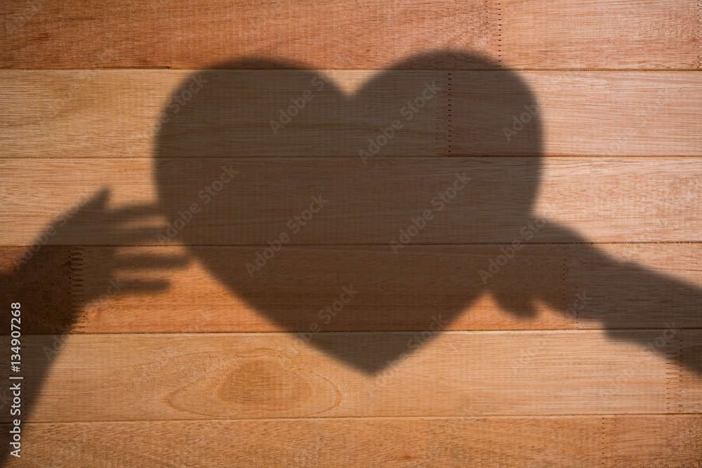 Composite image of hands holding orange heart shape paper