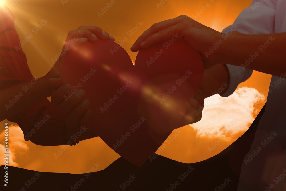 Composite image of couple holding a heart