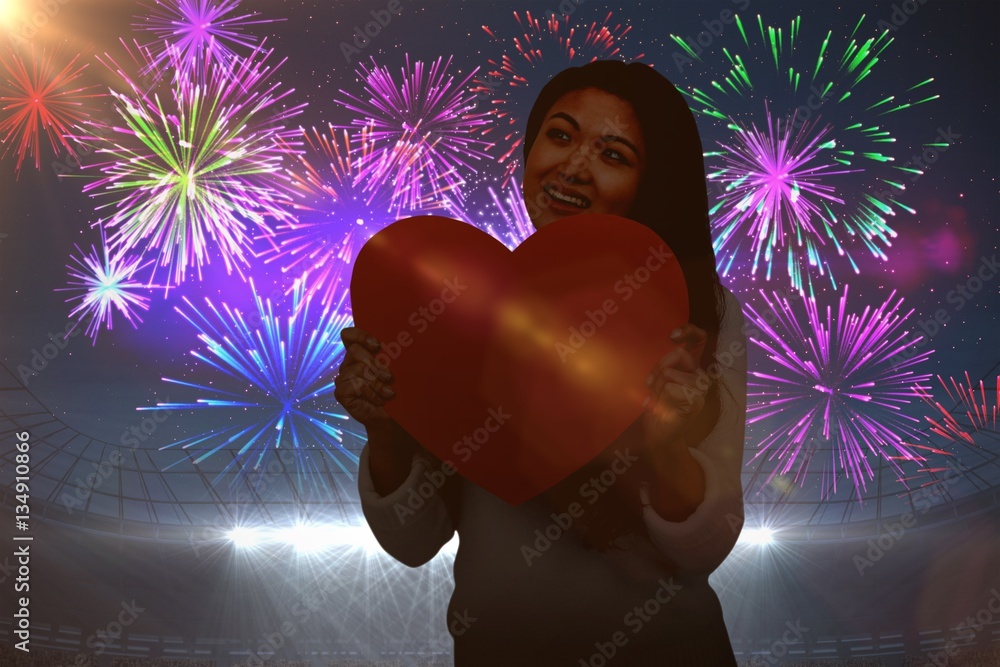 Composite image of smiling asian woman holding paper heart